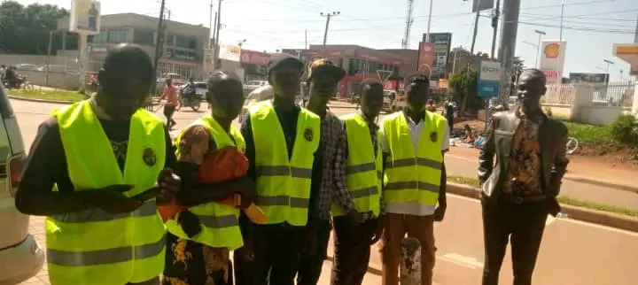 Group of young outreach volunteers in reflector vests standing along a town street